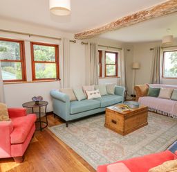 A living room with two coral armchairs a blue sofa a patterned sofa and a wooden coffee table at Oak Apple Cottage in Presteigne