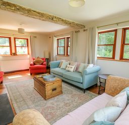 A living room with sofas and armchairs around a wooden coffee table at Oak Apple Cottage in Presteigne