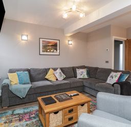 A living room with a gray sectional sofa and colorful pillows a wooden coffee table and a light blue armchair at Quarters Ambleside