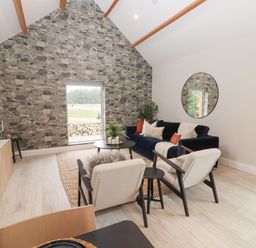 A living room with stone accent wall window blue sofa chairs round mirror and TV at Curhoor Near Loughrea County Galway