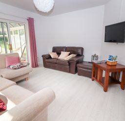 A living room with beige and brown sofas a wooden table and a wall-mounted TV at Tonakilla House in Tonakilly near Camp County Kerry