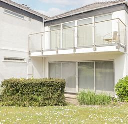 The exterior of a white two-story building with glass doors and a balcony with a chair and railing at 23 Coedrath Park in Saundersfoot