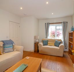 A living room with two sofas a wooden coffee table a lamp a bookshelf and a window at Sea Breeze in Swanage