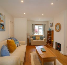 A living room with two sofas a wooden coffee table a bookcase and a small fireplace at Sea Breeze in Swanage