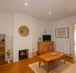 A living room with a coffee table a small fireplace wooden furniture and a television at Sea Breeze in Swanage