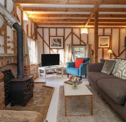 A living room with a wood stove blue armchair and a gray sofa at Twosome in Chediston near Halesworth