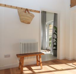A hallway with a wooden bench and coat rack with a bag hanging at The Apple Shed in Upexe near Silverton