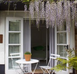 An outdoor seating area with a white table and two chairs under hanging flowers at The Apple Shed in Upexe near Silverton