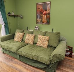 A living room with a green sofa and wall art at Flodden Apartment in Wooler