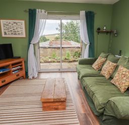 A living room with a television and sofa at Flodden Apartment in Wooler
