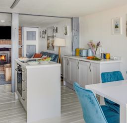 A kitchen and dining area with blue chairs and a fireplace in the background at The Cubby Hole in Sennen Cove