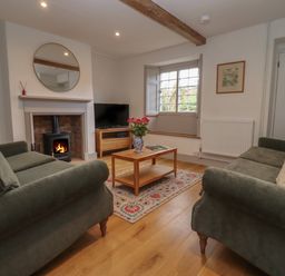 A living room with two sofas a coffee table and a fireplace at Blossom Cottage in Chipping Campden