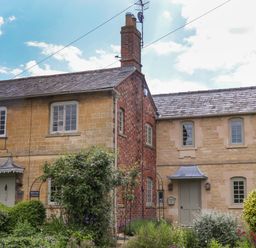A stone and brick exterior of a cottage with garden and bushes at Blossom Cottage in Chipping Campden