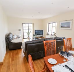A living room with brown leather sofas facing a television and a dining table with plates and glasses at Doonalton House in Dromore West County Sligo
