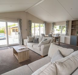 A living room with sofas a coffee table dining table and shelves at Lodge 3 in St Asaph