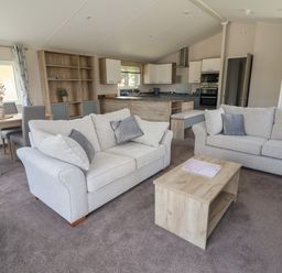 A living room with two sofas a coffee table and a dining table in an open plan layout at Lodge 3 in St Asaph