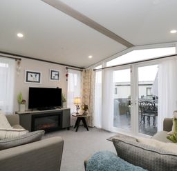 A living room with sofas a television and sliding glass doors leading outside at Tiggywinkles in Chipping Norton