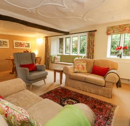 A living room with sofas, armchair, window seat, and dining table at The Elbow in Frampton