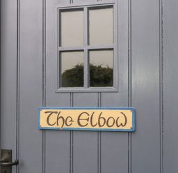A door with a window and a sign that reads The Elbow at The Elbow in Frampton