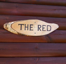 A wooden plaque with the text The Red at The Red in Llanerch Park near St Asaph