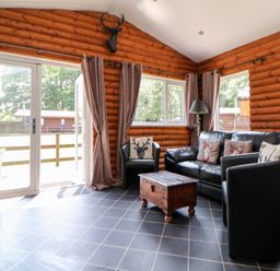 A snug with a leather sofa and wooden coffee table at The Fallows in Llanerch Park near St Asaph