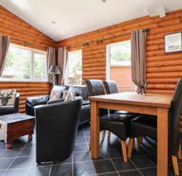 A living room with a sofa, coffee table, and dining table at The Fallows in Llanerch Park near St Asaph