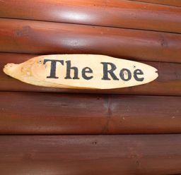 A wooden sign with the text The Roe on a wooden surface at The Roe near Llanerch Park near St Asaph