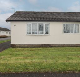 Exterior of a single-story house with tiled roof grass lawn and two sets of windows at 48 Gower Holiday Village in Scurlage