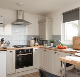 A kitchen with a gas stove oven microwave sink and dining area at Bushwood Lodge in Wendron near Helston