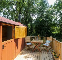 A wooden deck with a table and two chairs outside a cabin at The Foxes Den Shepherds Hut in Oldbury-On-Severn