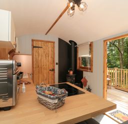 A kitchen with wooden countertops a microwave stove and a door leading to a wooden deck at The Foxes Den Shepherds Hut Oldbury-On-Severn