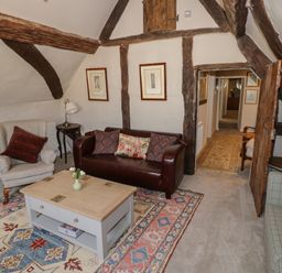 A sitting room with armchairs sofas a coffee table and wooden beams at The Bindery in Broadway