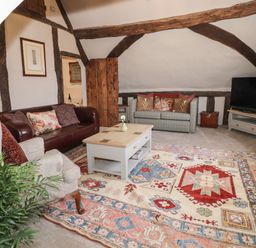A living room with sofas armchair coffee table television and a patterned rug at The Bindery in Broadway