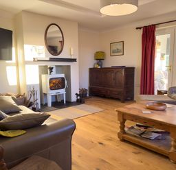 A living room with a leather sofa and a wood-burning stove at Crogal Farmhouse in New Quay