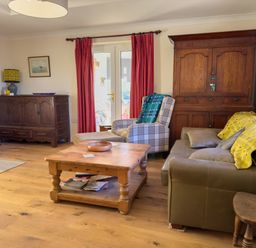 A living room with wooden furniture and red curtains at Crogal Farmhouse in New Quay