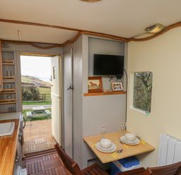 A kitchen and dining area with wooden cabinets and table set for two at Sea the Stars in New Quay