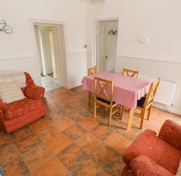 A dining room with a table covered in a red and white checkered tablecloth and four wooden chairs with two red upholstered armchairs at Marys Cottage Theur near Riverstown County Sligo