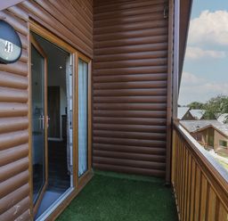 A balcony with artificial grass and wooden railing outside a wooden cabin at Premier Lodge 41 in Dyserth