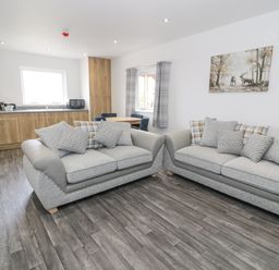 A living room with two sofas and a dining table next to a kitchen area at Luxury Lodge 46 in Dyserth