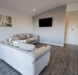 A living room with two grey sofas with cushions a wall mounted television and a painting of deer on the wall at Luxury Lodge 53 in Dyserth