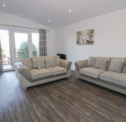 A living room with two sofas and a painting on the wall at Luxury Lodge 53 in Dyserth