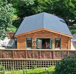 A log cabin with a deck and chairs at Owl Lodge Menheniot