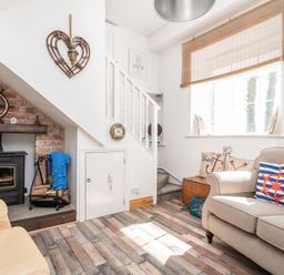 A living room with a fireplace under stairs and sofas with nautical cushions at The Old Coastguard Tower Buncrana County Donegal