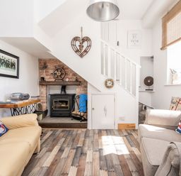 A sitting room with two sofas wooden flooring a wood stove and stairs at The Old Coastguard Tower Buncrana County Donegal