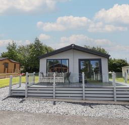 A single story house with a patio deck and glass railing at Lodge 9 in St Asaph