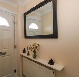 A hallway with a front door and a mirror at No 8 Burnham-on-Sea