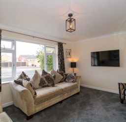 A living room with a sofa, armchair, and television at No 8 Burnham-on-Sea