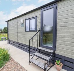 Exterior side view of a small building with steps leading to a frosted glass door and a small window at The Hoot Great Finborough near Stowmarket