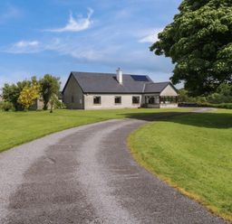 A single story house with a curved gravel driveway surrounded by grass and trees at Bunny Lane in Cloonflynn near Ballycarra County Mayo