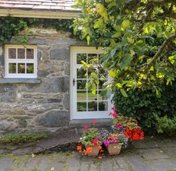 An entrance with flowers and stone wall at Royal Oak Farm Cottage in Betws-y-Coed